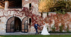 Un cuplu de miri fericiti fotografiindu-se in aer liber in fata unui conac istoric, o locatie nunta bucuresti superba pentru evenimente rustice si elegante.