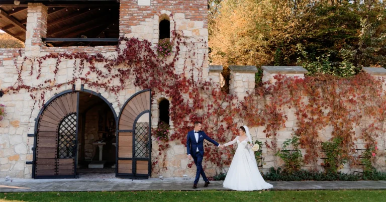 Un cuplu de miri fericiti fotografiindu-se in aer liber in fata unui conac istoric, o locatie nunta bucuresti superba pentru evenimente rustice si elegante.